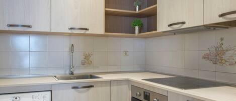 A modern kitchen with a built-in washing machine, oven, and a stainless steel sink.