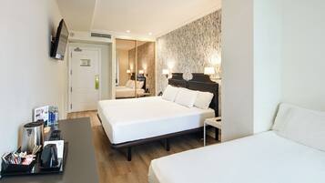 Hotelkamer met twee bedden, een televisie, een bureau met koffiezetapparaat en telefoon, en een badkamer zichtbaar door een geopende deur.