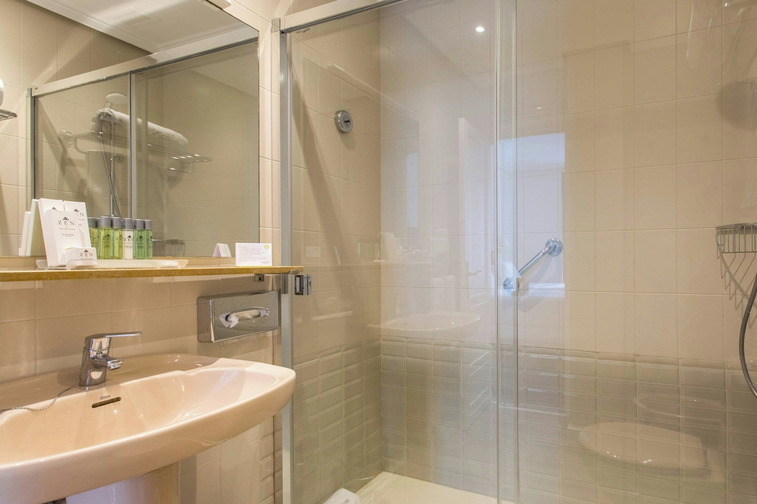 A modern bathroom with a glass-enclosed shower, a sink, and toiletries on the counter.
