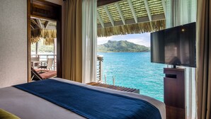 Een hotelkamer met een bed, een televisie en uitzicht op de oceaan.