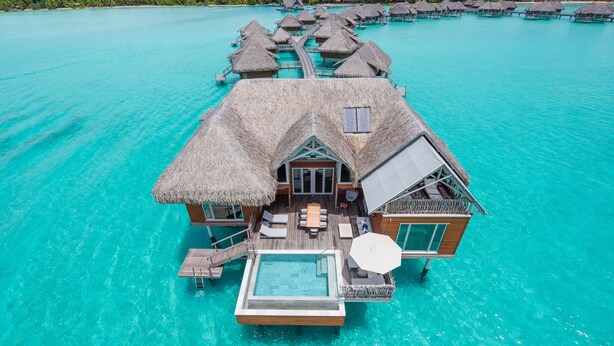 Overwater bungalows met zwembad, houten terras en rieten daken.