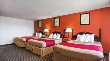 Habitación de hotel con tres camas, cada una con cabecera y lámparas de noche.