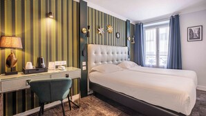 Een hotelkamer met een groot bed, een bureau met stoel, een lamp en een raam met gordijnen.