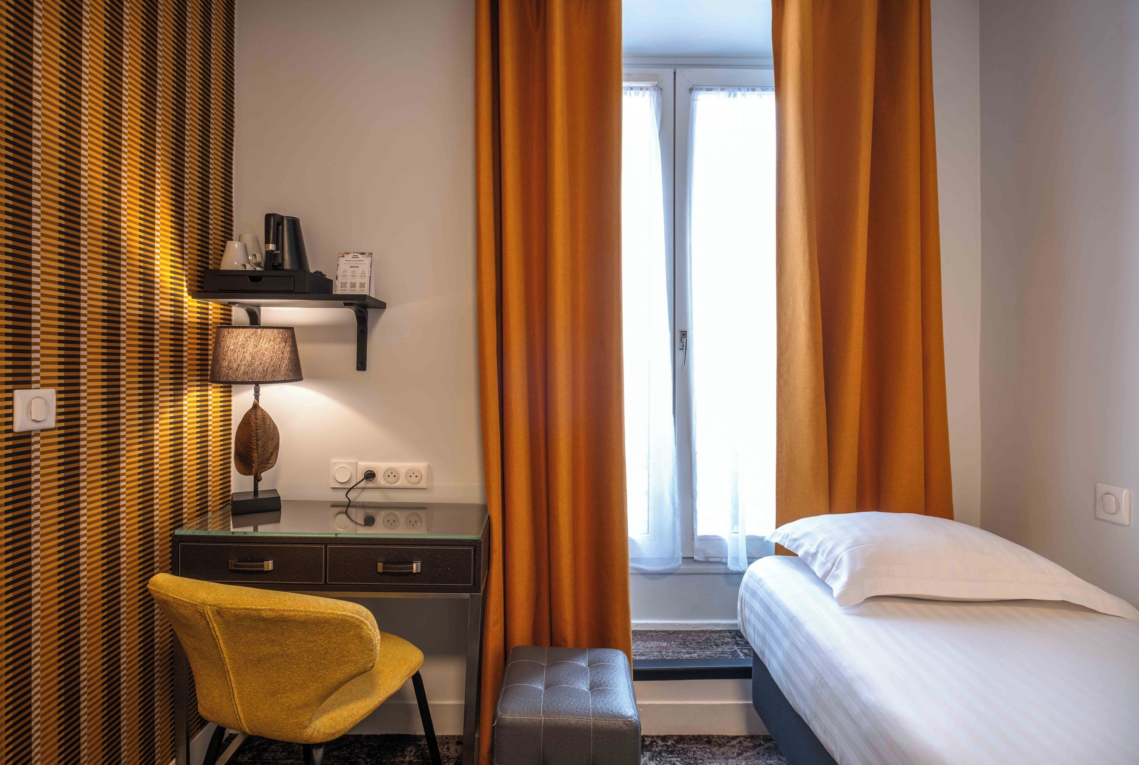 A hotel room with a desk, chair, and bed.