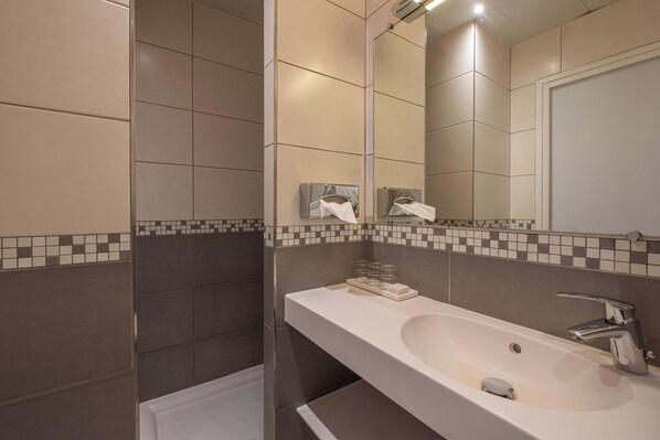 Une salle de bain moderne dotée d’un grand lavabo, d’un miroir et d’un distributeur de serviettes.