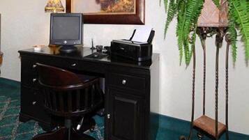 A wooden desk with a computer, a lamp, and a plant.