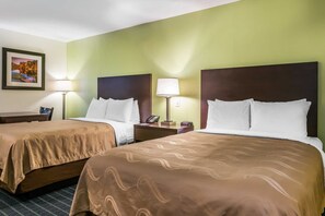 A hotel room with two beds, each with a brown bedspread, a nightstand with a lamp, and a framed picture on the wall.