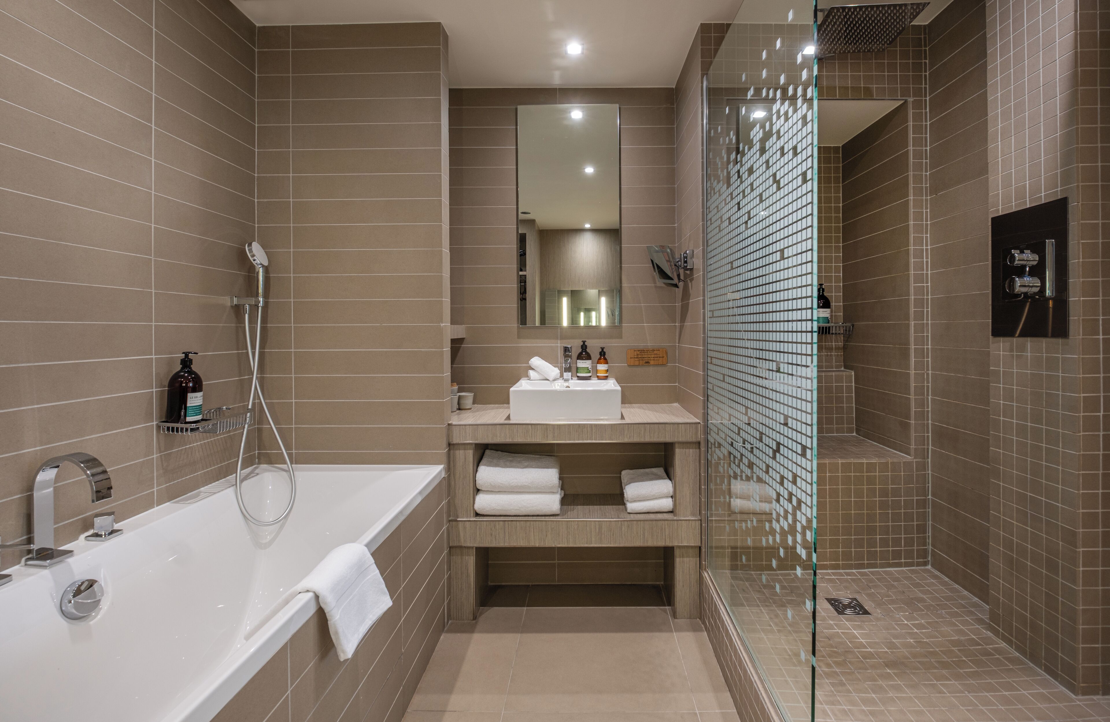 A modern bathroom with a bathtub, a glass-enclosed shower, and a vanity with a mirror.