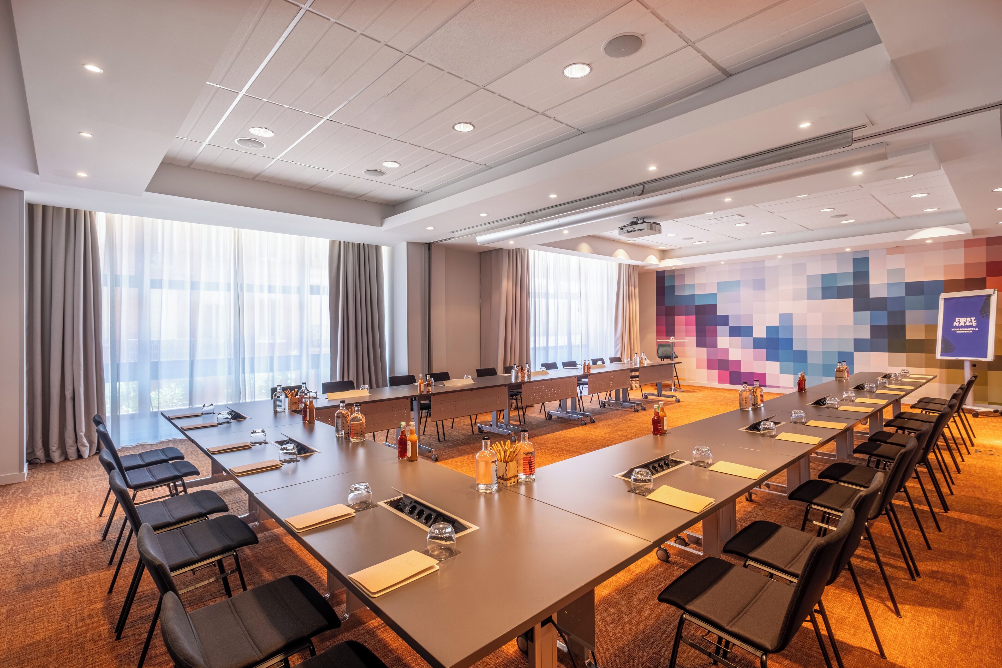 Une salle de conférence équipée de longues tables, de chaises et d’un écran de projection.