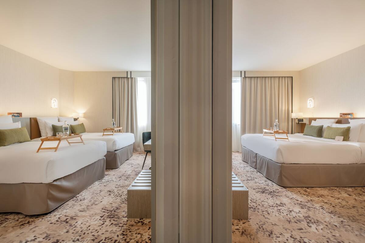 A hotel room with two beds, a large mirror, and a carpeted floor.