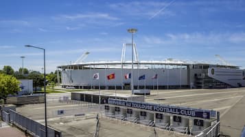 En stor stadion med flera flaggor, en överbyggd entré och en skylt som välkomnar besökare till fotbollsklubben.