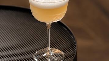Un cocktail servi dans un verre à pied, sur une table ronde dont le plateau est perforé.
