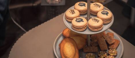 Suporte de três andares com macarons e biscoitos variados sobre uma mesa redonda.
