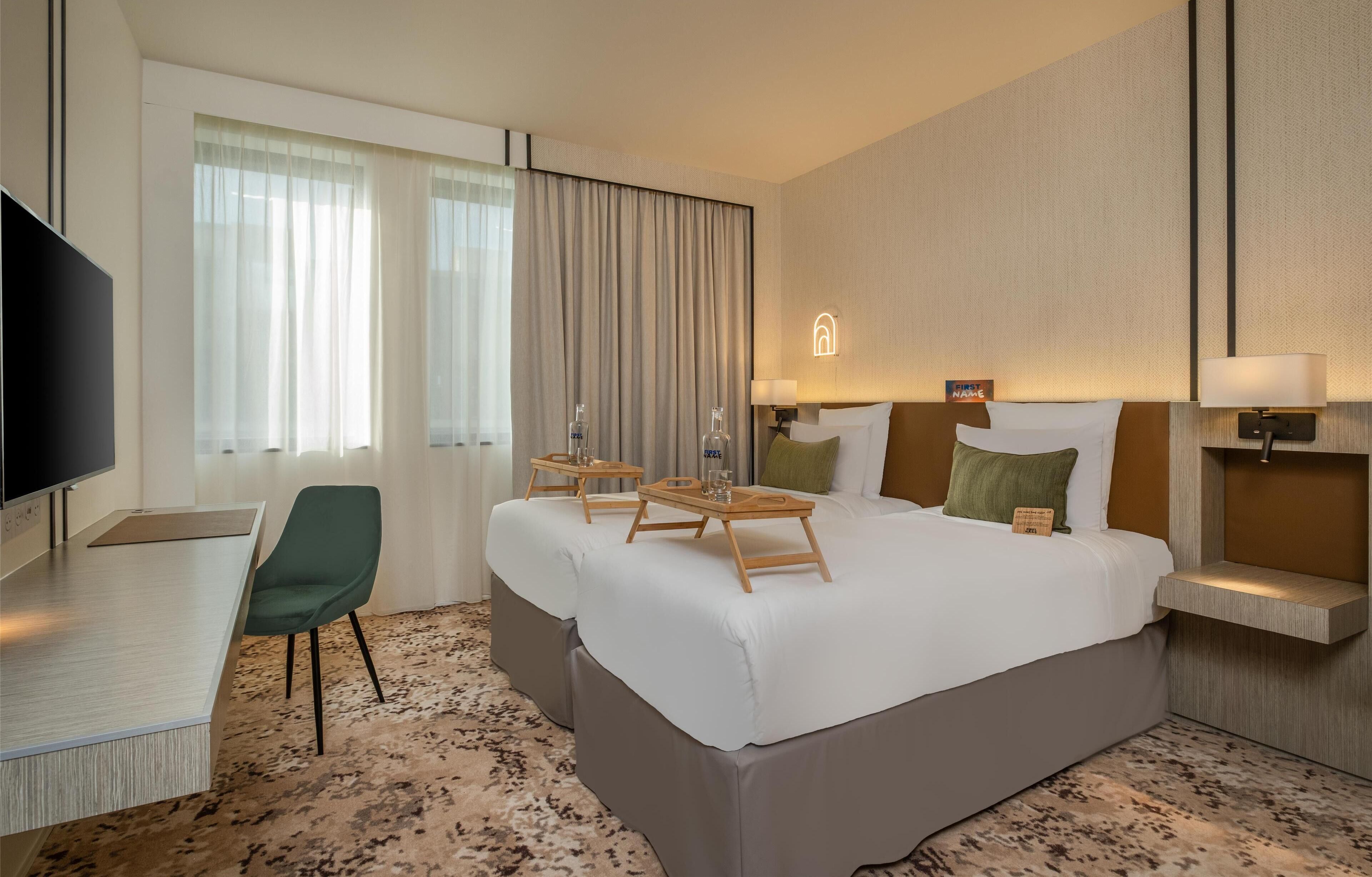 A hotel room with a large bed, a desk, a chair, and a television.