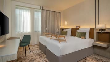 A hotel room with a large bed, a desk, a chair, and a television.