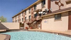 A building with a swimming pool, a staircase, and satellite dishes on the roof.