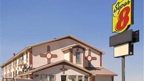 A motel with a distinctive cross-shaped design, a large Super 8 sign, and a clear sky.
