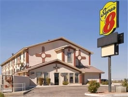 Un motel con un diseño distintivo en forma de cruz, un gran letrero de Super 8 y un cielo despejado.