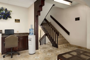 A reception area with a desk, computer, water cooler, and a staircase.