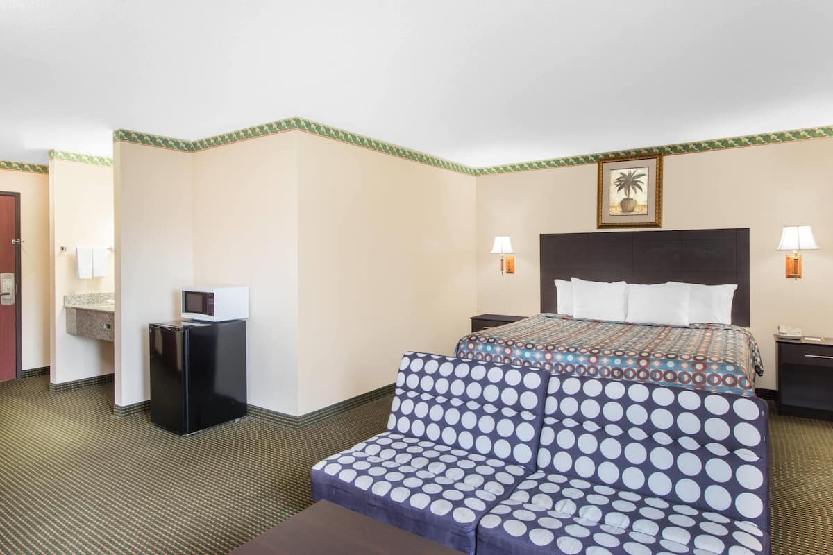 Ein Hotelzimmer mit Bett, einer Sitzecke, einem Schreibtisch mit Computer und einer Mikrowelle.