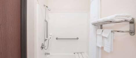 A bathroom with a shower, a bathtub, and a towel rack.