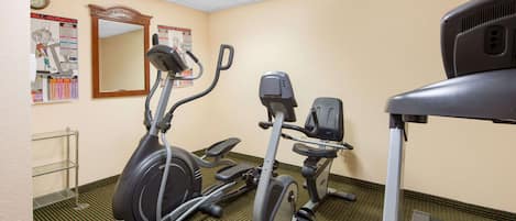 A fitness room with two stationary bikes, a treadmill, and a wall-mounted mirror.