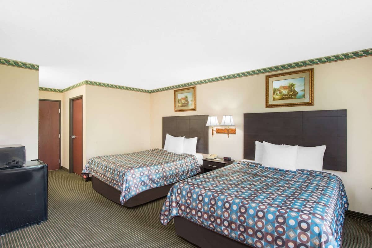 Ein Hotelzimmer mit zwei Betten, einem Schreibtisch und einem Fernseher.