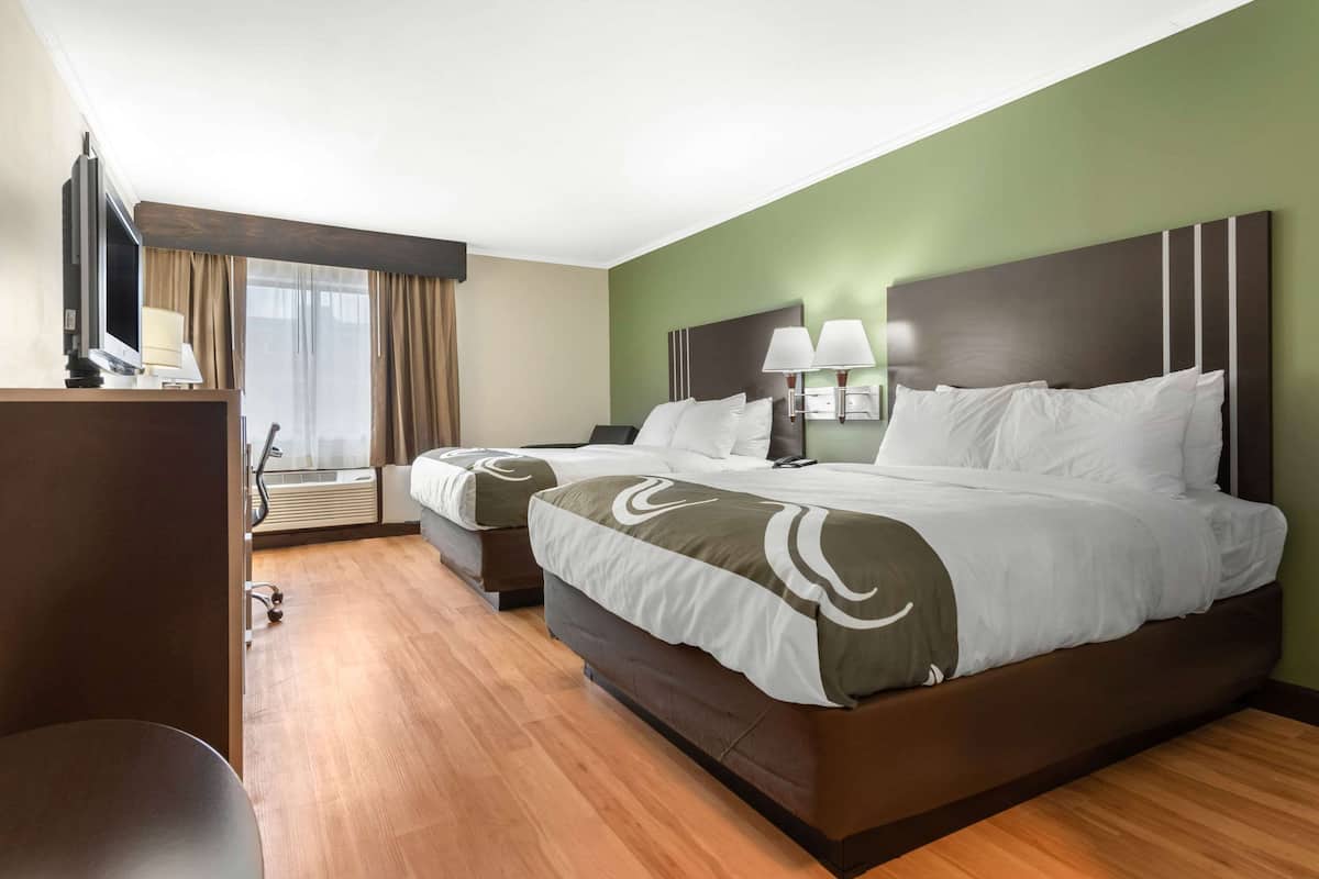 A hotel room with a large bed, a desk, and a TV.