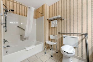 A bathroom with a walk-in shower, a toilet, a chair, and a towel rack.