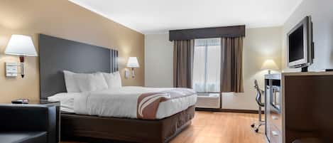 A hotel room with a bed, bedside lamps, a TV, a desk, and a chair.