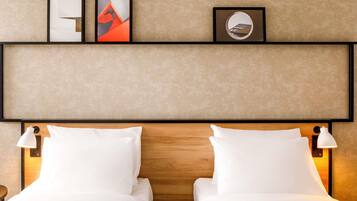 A hotel room with two beds, a wooden headboard, wall-mounted artwork, and bedside lamps.