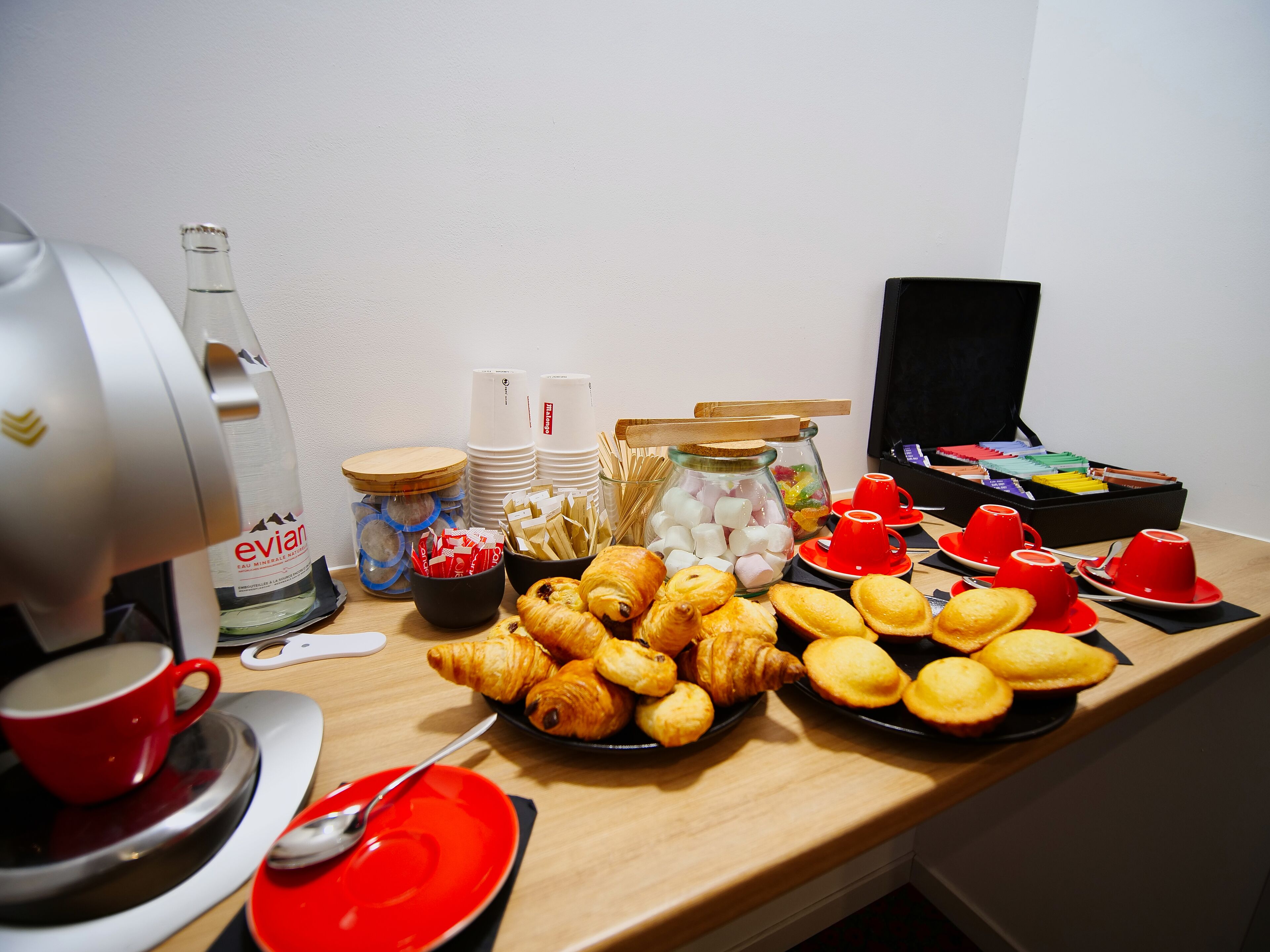 Un bufé de desayuno con croissants, muffins y una máquina de café.