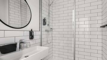 Een moderne badkamer met een wit wastafelmeubel, een spiegel en een douchecabine met glazen wanden.