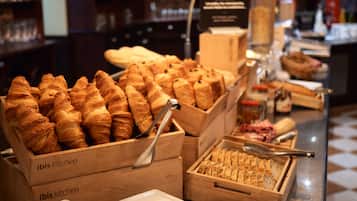 A buffet with various baked goods and bread displayed in wooden boxes labeled "ibis kitchen".