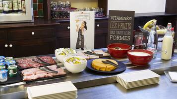 A buffet with various food items, including meats, cheeses, and fruits.