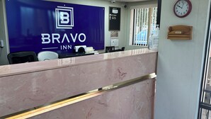 A reception desk at Bravo Inn with a marble counter, a clock, and a mailbox. - Bravo Inn Greensboro (Greensboro)