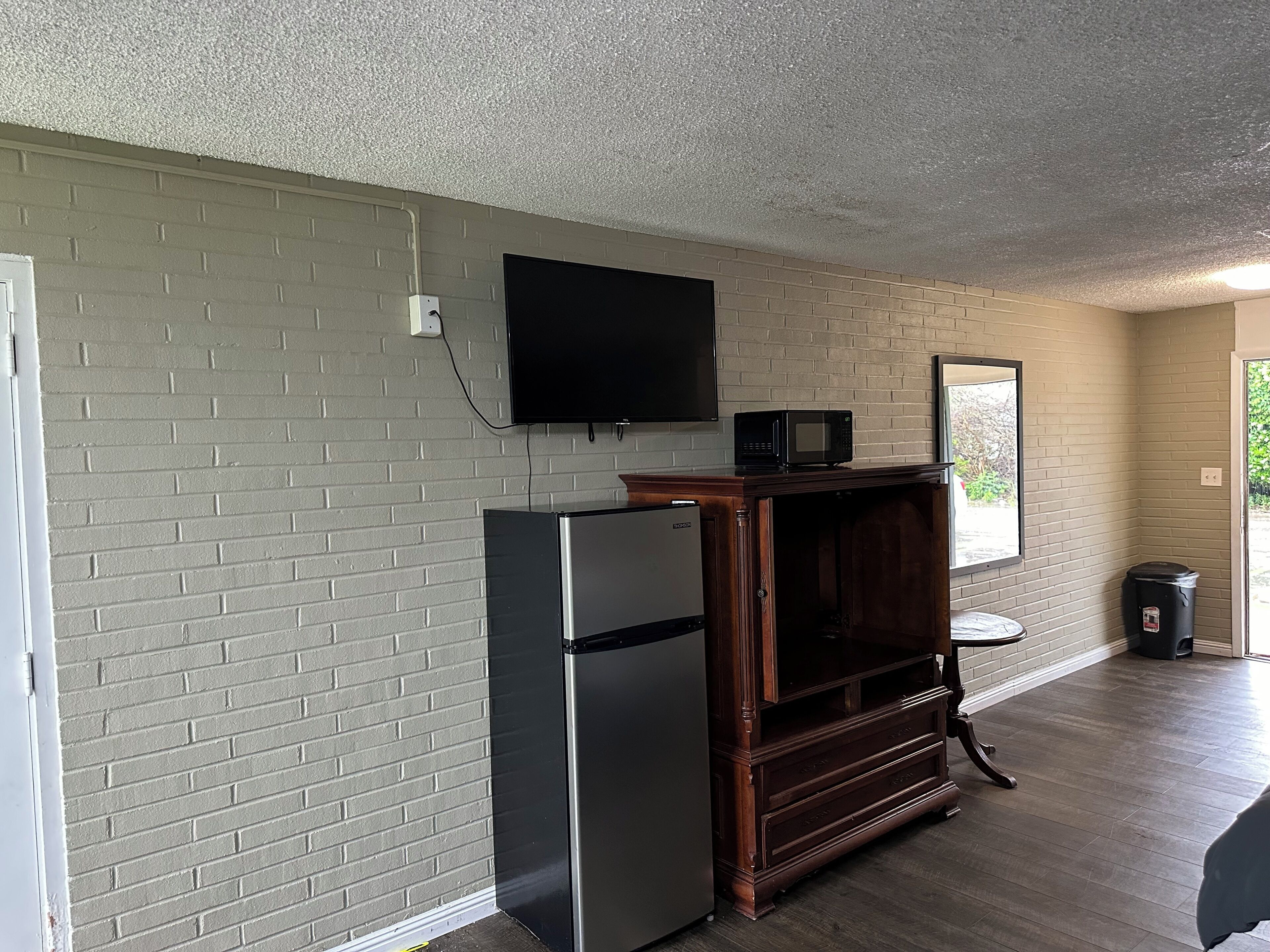 A compact kitchen with a refrigerator, microwave, and a wooden cabinet.