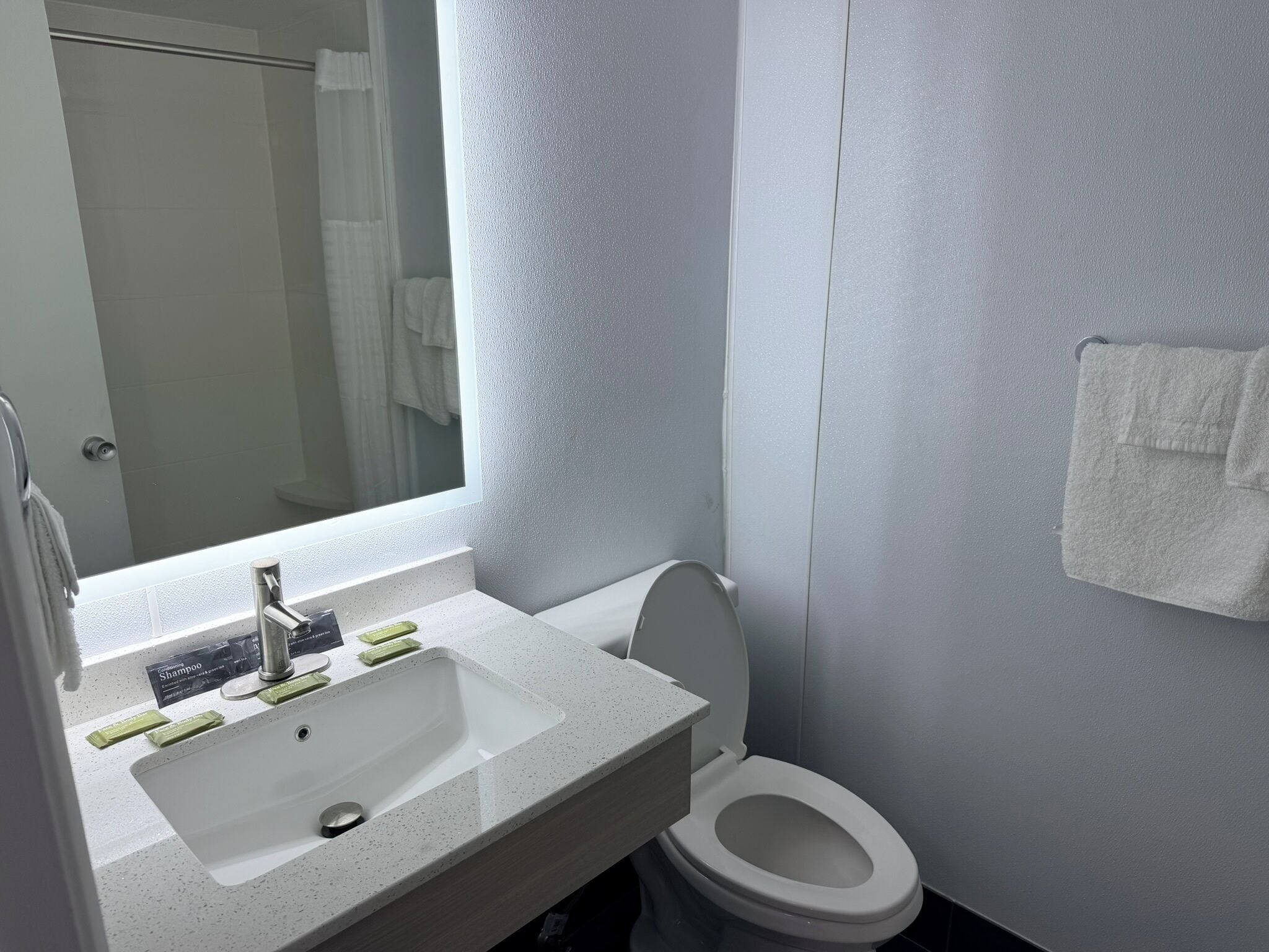 A bathroom with a sink, mirror, toilet, and towel rack.