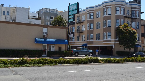 A multi-story hotel with a prominent sign for 'Alpha Inn & Suites'.