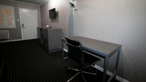 A room with a desk, chair, and a mounted television.