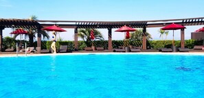 A swimming pool with red umbrellas and lounge chairs. - AoAwo Naruto Resort (Naruto)