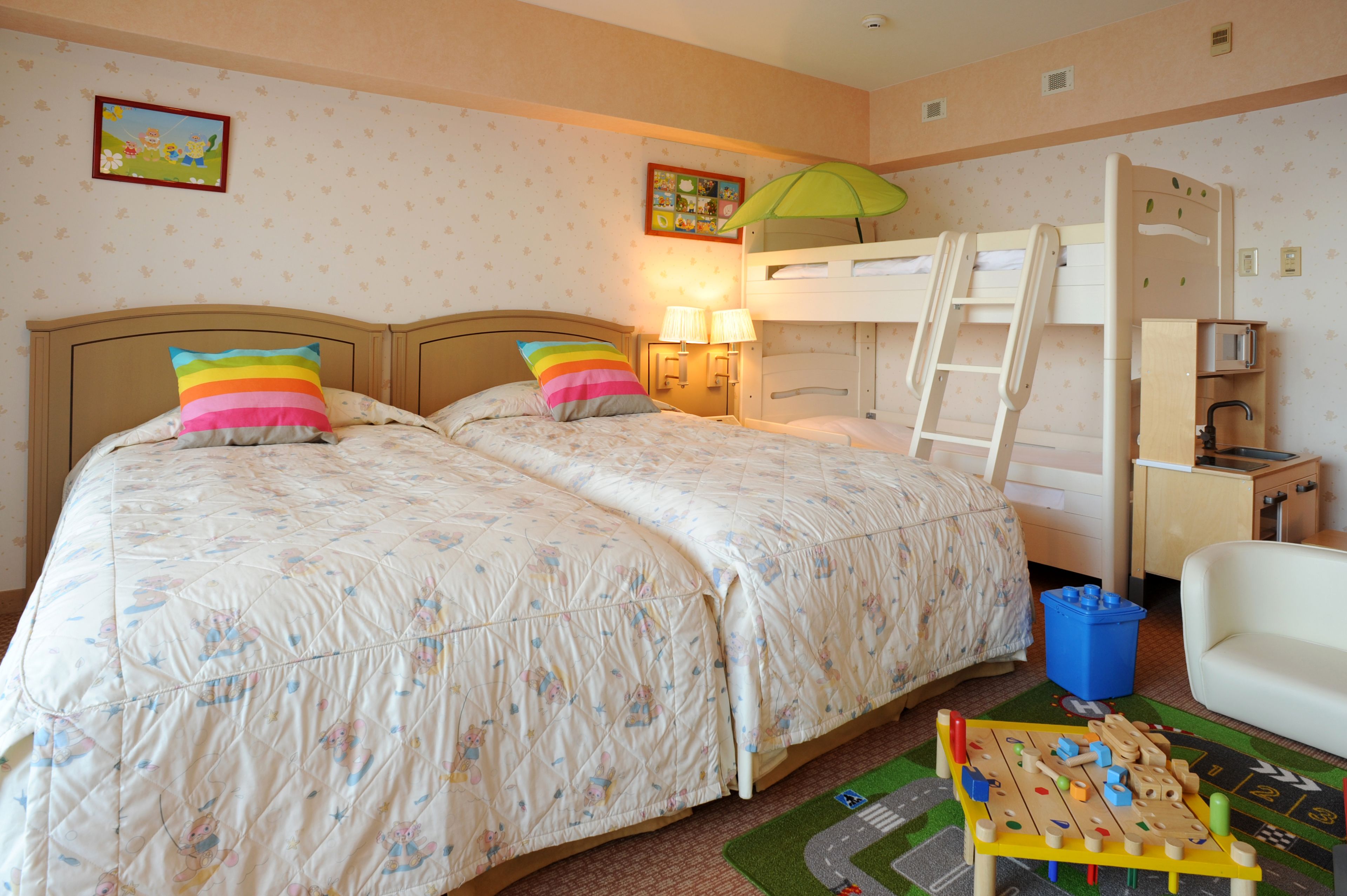 A bedroom with two beds, a bunk bed, a small table with toys, and a chair.