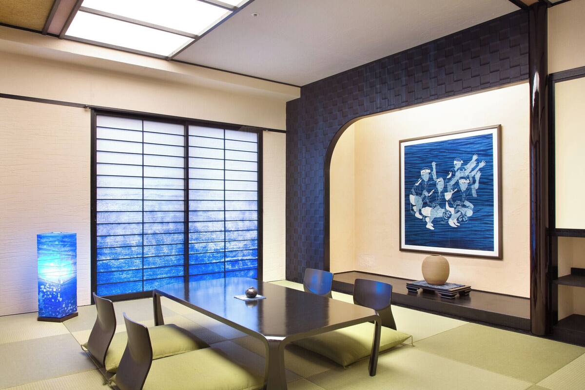 A modern meeting room with a large table, chairs, a decorative vase, and a framed artwork on the wall.