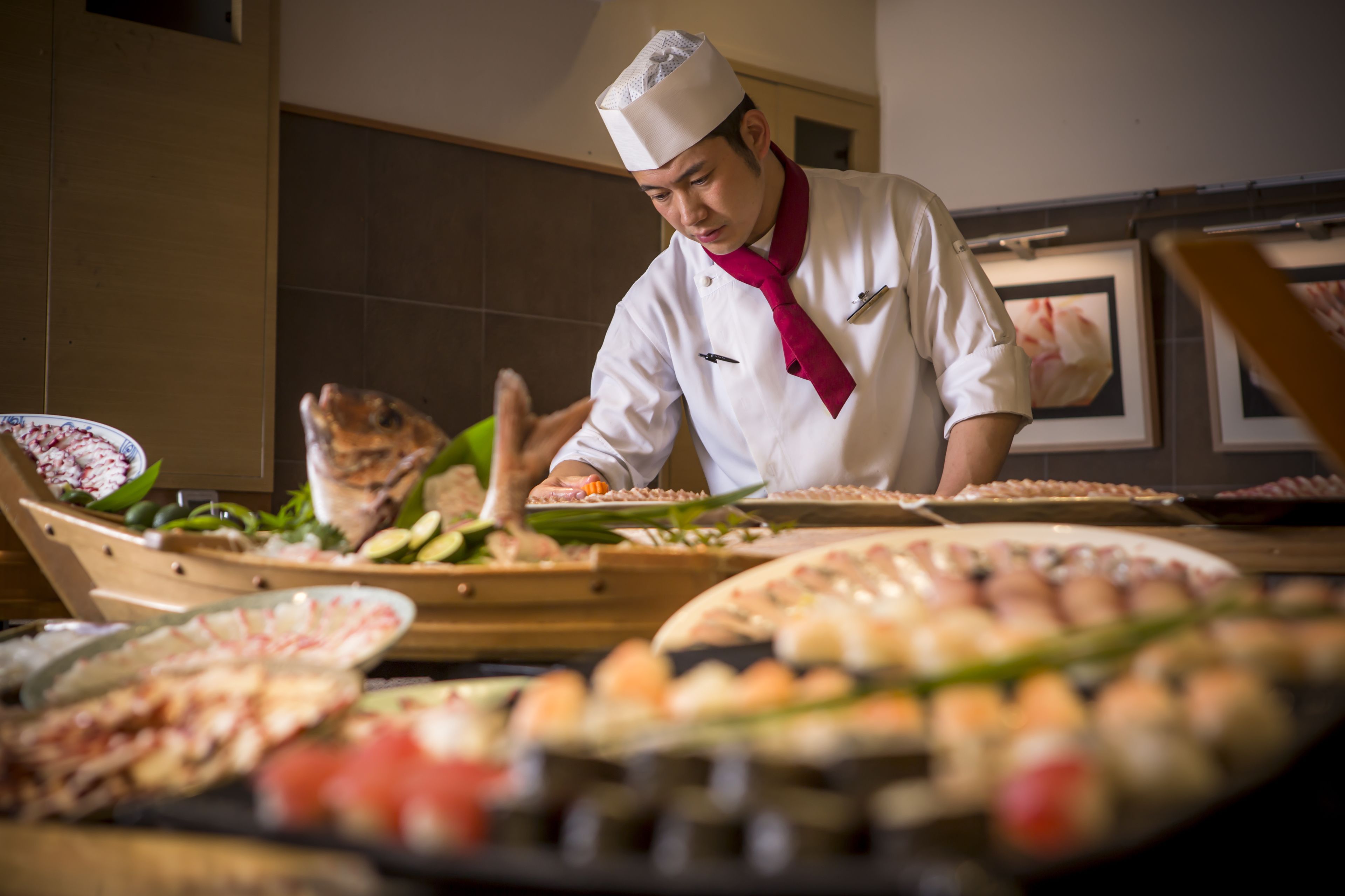 A chef preparing food in a kitchen with various dishes and ingredients on the counter.