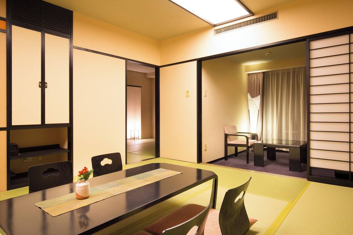 A traditional Japanese-style room with tatami flooring, a low table with chairs, and sliding doors.