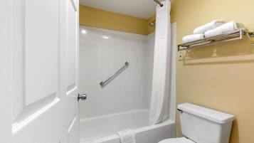 Une salle de bain avec une baignoire blanche, des toilettes blanches et un porte-serviettes avec des serviettes.
