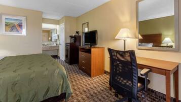 A hotel room with a bed, desk, chair, TV, and a mirror.