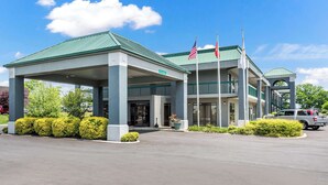 A hotel with a covered entrance, American flags, and a parking lot. - Quality Inn Lebanon (Lebanon)