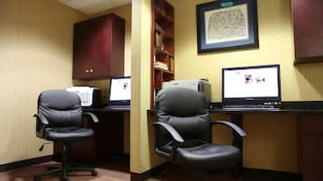 Un espace de travail comprenant deux chaises de bureau noires, un bureau et un écran d’ordinateur.