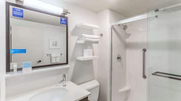 A modern bathroom with a glass shower enclosure, a sink, and a mirror.